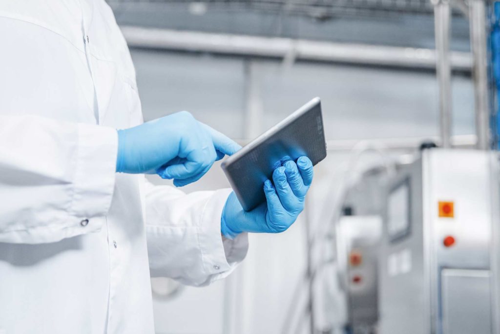 Facility worker with blue gloves checks ipad